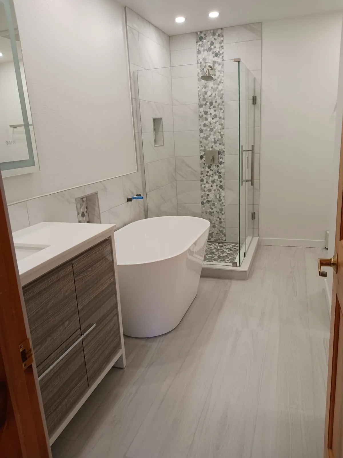 White bathroom with freestanding tub and pebble mosaic accent wall
