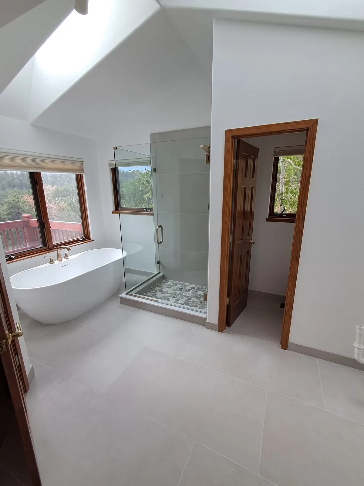 Master bath remodel with freestanding tub, glass shower and forest windows