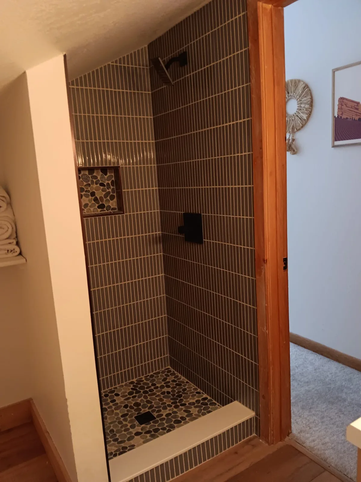 Vertical stack tile shower with pebble floor and pebble niche
