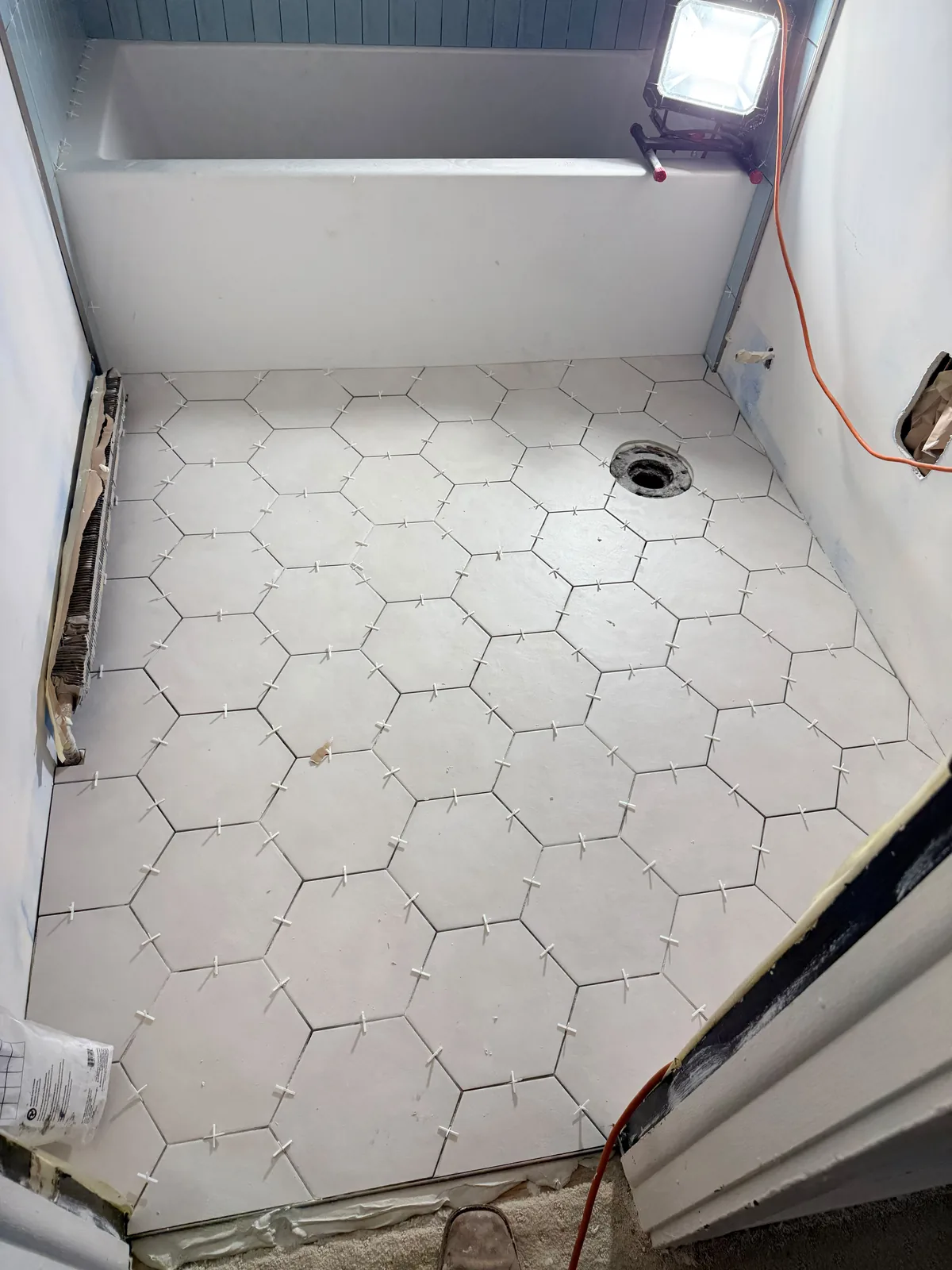 Hexagon floor tile being installed with spacers in a bathroom