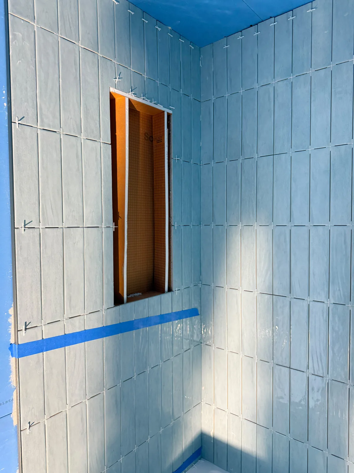 Vertical tile being set with spacers and level lines mid-install