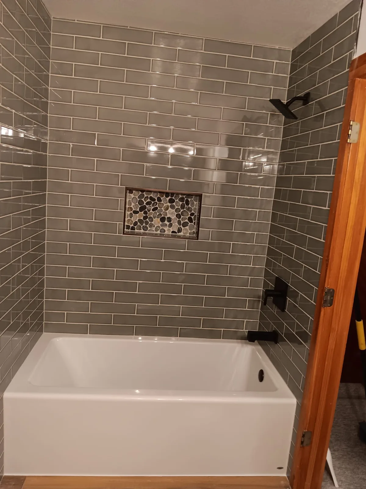 Sage subway tile tub surround with pebble niche